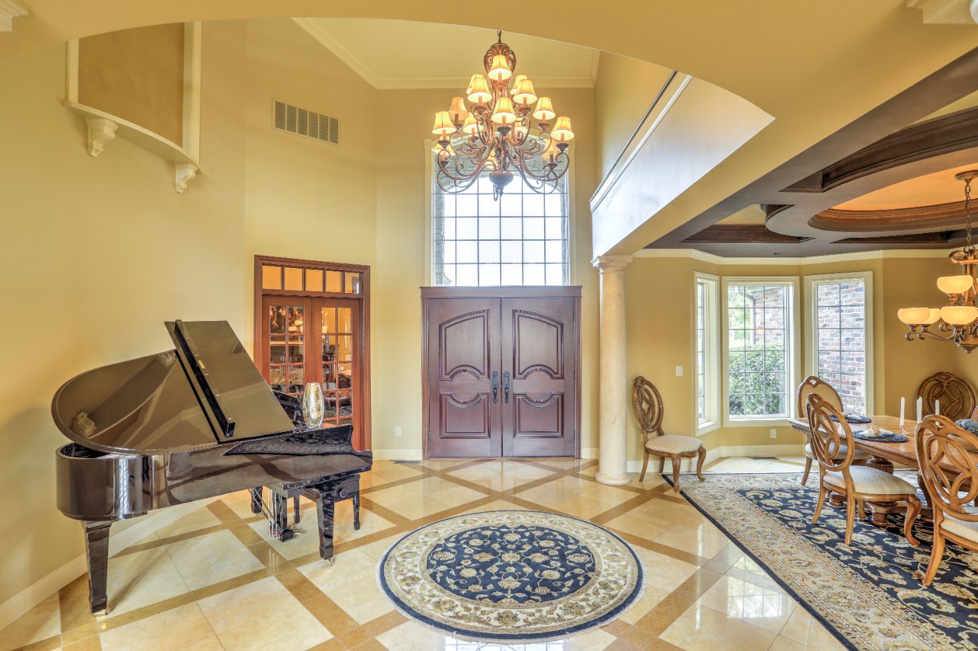 Two-story foyer with grand piano and chandelier